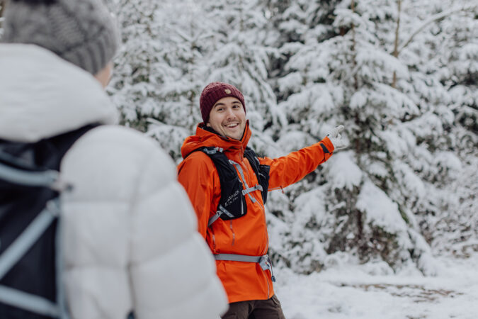 Ett ungt par i en snötäckt skog som vandrar John Bauerleden