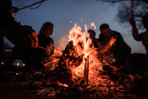 En grupp konferensgäster på Bauergårdens sitter vid en eld i mörkret och lagar mat efter en guidad vandring i John Bauers fotspår.