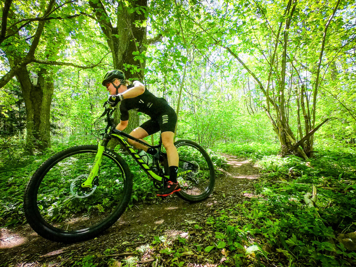 Cyklist på mountainbike cyklar genom Bauers grönskande skogsstigar, en perfekt aktivitet för konferensgäster nära Jönköping.