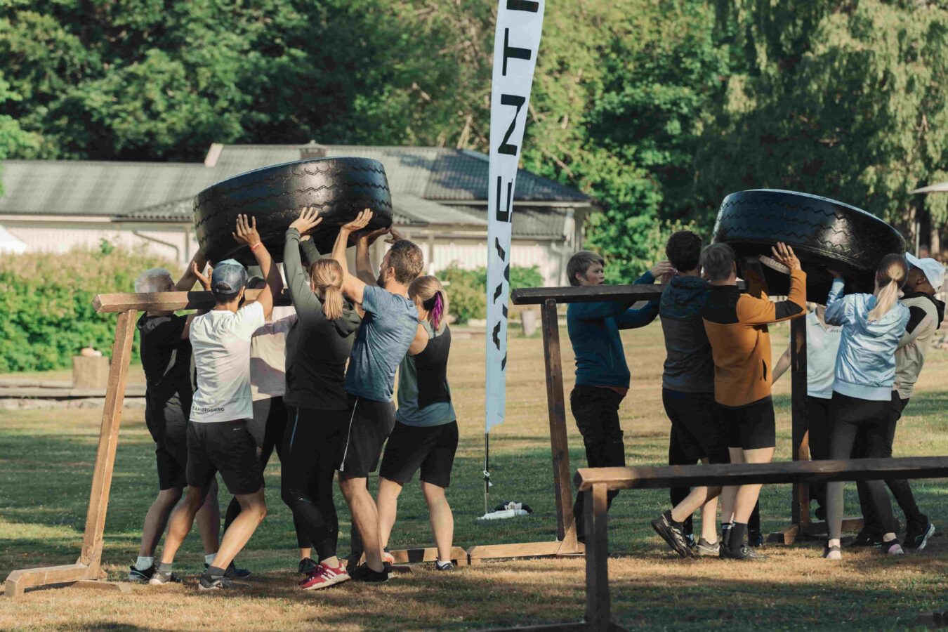 Företagsteam samarbetar för att lyfta en stor däck på en utomhus teambuildingaktivitet i Bauers trolska natur, nära Jönköping.